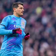 Bramkarz Real Madryt w błękitnym stroju, z różowymi rękawicami, gotowy do obrony. W tle tłum kibiców, symbolizujący drogę do kolejnych trofeów Real Madryt.