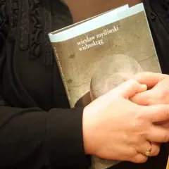 Dwie osoby trzymają książkę "Widnokrąg" Wiesława Myśliwskiego.