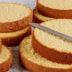Dischi di pan di spagna dorati e soffici, pronti per essere farciti. Un coltello da pane è appoggiato su uno strato.