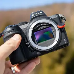 Dłoń trzyma aparat Nikon Z5 z widocznym sensorem, gotowy do testów w plenerze.