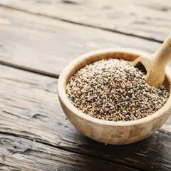 Ciotola di legno piena di quinoa tricolore, un legume nutriente, con un mestolo di legno.