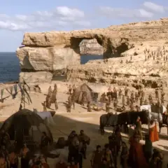 En scen från Game of Thrones på Malta, med en stor folkmassa och tält vid havet under en klippformation.