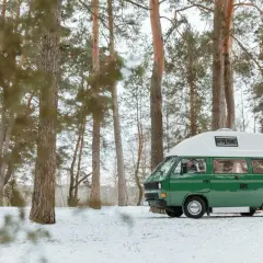 Zielony kamper zaparkowany w zimowym lesie nad Zalewem Koronowskim.