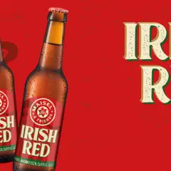 Zwei Flaschen "Irish Red" Bier vor rotem Hintergrund mit Harfenmotiv. Was ist Rotbier? Dieses Irish Red Ale ist vollmundig, aromatisch und süffig.