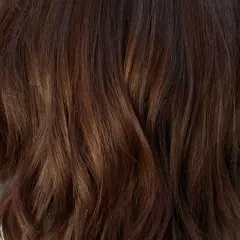 Cheveux bruns ondulés avec des reflets subtils. Une question se pose : comment enlever une patine cheveux pour retrouver une couleur naturelle ?