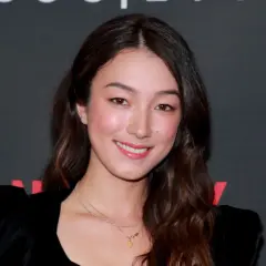 Natasha Liu Bordizzo ler glatt i en svart klänning med puffärmar.