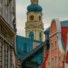Architektura Rygi zachwyca. Zobaczysz tu zabytkowe kamienice i nowoczesne budynki, a w oddali wieżę zegarową.