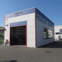 Budynek stacji kontroli pojazdów z napisem "Przeglądy Rejestracyjne" i otwartą bramą wjazdową.