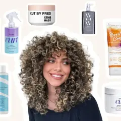 Une femme aux cheveux bouclés souriante, entourée de produits capillaires. Trouvez votre **boucle musique gratuite** avec ces soins pour cheveux.