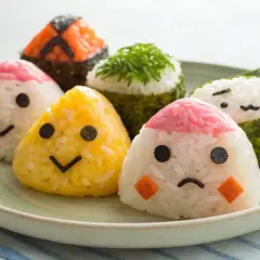 Cute onigiri with faces on a plate. If your onigiri falls apart, try using stickier rice and pressing it firmly.