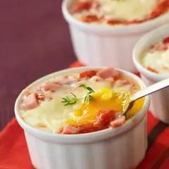Œufs cocotte au four, jambon et fromage fondus, un délice crémeux prêt à être dégusté.