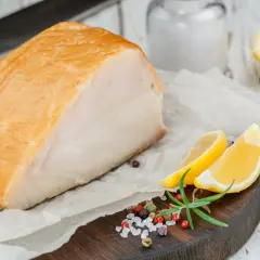 Un beau morceau de haddock fumé, prêt pour la cuisson, accompagné de quartiers de citron, de romarin et d'un mélange de poivre et de sel.