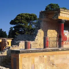 Ruinas del palacio de Cnosos con sus icónicas columnas rojas y un fresco de toro.