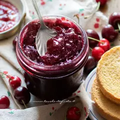 Un barattolo pieno di deliziosa marmellata di ciliegie, pronto per essere spalmato su fette biscottate.