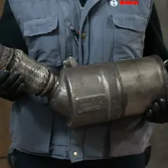 Mechanik w rękawiczkach trzyma zużyty DPF. Jak rozpoznać wypalanie DPF? To kluczowe dla sprawności silnika.