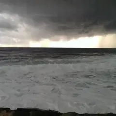 Burzowe niebo nad wzburzonym morzem w Pafos. Grudzień przynosi dramatyczne chmury i deszcz na horyzoncie.