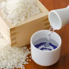 Nalewanie sake do czarki. Obok drewniane naczynie z ryżem, z którego powstaje ten alkohol. Zastanawiasz się, sake ile procent?