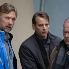 Tomas Fryk, med blodfläckar i ansiktet, står med två andra män. En pratar i telefon.