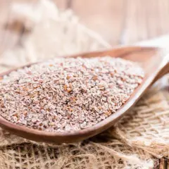Semi di psillio su un cucchiaio di legno, utili per la regolarità intestinale ma con psillio controindicazioni da conoscere.