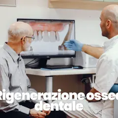 Dentista mostra a paziente un modello 3D di denti e mascella, spiegando la rigenerazione ossea dentale.