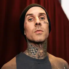 Travis Baker w czarnej czapce beanie, z tatuażami na twarzy i szyi, w tym wizerunkiem Marilyn Monroe.