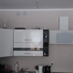Dwie kratki wentylacyjne w jednym kominie nad białą zabudową kuchenną.