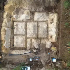 Budowa fundamentów domu w lesie. Widać zbrojenie i szalunki. W tle drzewa. To etap prac poprzedzający badania geotechniczne gruntu.