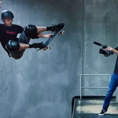 Tony Hawk w locie na deskorolce, filmowany przez operatora kamery.