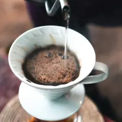 Gorąca woda powoli przelewa się przez mieloną kawę w dripperze, tworząc aromatyczną kawę po gruzińsku.
