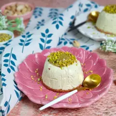 Delizioso semifreddo al pistacchio, guarnito con granella e crema di pistacchi, servito su un piatto rosa.