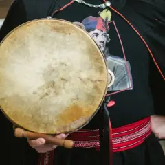 Mateusz Dobrowolski trzyma bębenek. Na czarnej koszulce widnieje wizerunek mężczyzny w kolorowej czapce.