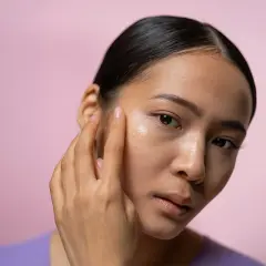 En kvinna applicerar en kräm i ansiktet, kanske en retinolkräm för ett strålande retinol ansikte.