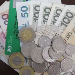 Złotówki i monety, a obok zielona legitymacja ZUS. Zastanawiasz się, ile wynosi 13 emerytura?