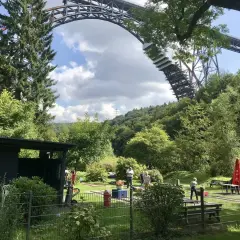 Familien genießen ein **adventure minigolf nrw** unter der imposanten Eisenbahnbrücke.