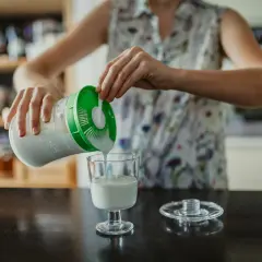 Persona sirve kéfir en un vaso. ¿Cuándo tomar kéfir antes o después de las comidas?
