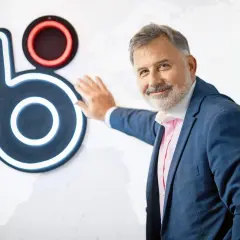 Mężczyzna w garniturze opiera się o logo, które może sugerować, kto wymyślił BLIK.