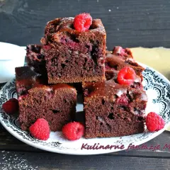 Wilgotne ciasto czekoladowe z malinami i galaretką, udekorowane świeżymi malinami. Idealne na deser.
