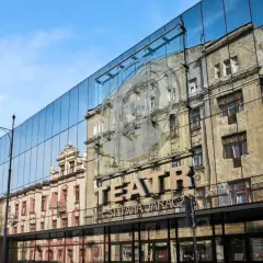 Teatr Jaracza w Łodzi, z nowoczesną szklaną fasadą odbijającą zabytkową architekturę. Sprawdź repertuar!