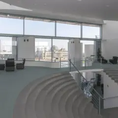 Modernes Foyer im Bundeskanzleramt mit Blick auf das Reichstagsgebäude. Sitzgruppen und eine geschwungene Treppe laden zum Verweilen ein.