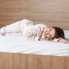 Uśmiechnięta kobieta w piżamie śpi na łóżku z materacem z naturalnego lateksu.