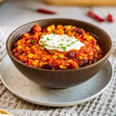 Herzhaftes Chilli sin Carne mit Mais, Bohnen und Linsen, garniert mit einem Klecks Sauerrahm und Schnittlauch.