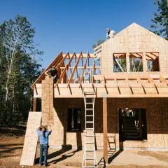Construcción de una casa de madera, con obreros colocando tableros. El proceso de saber cuanto cuesta hacer una casa es complejo.