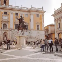Piazza del Campidoglio a Roma, con la statua equestre di Marco Aurelio e turisti che ammirano l'architettura rinascimentale.