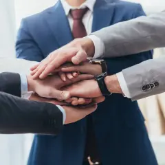 Zespół składa dłonie, symbolizując jedność i siłę. To jak prokura samoistna – wspólne działanie dla dobra firmy.
