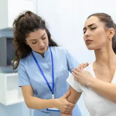 Lekarka bada ramię pacjentki, która odczuwa ból. To może być etap badania na osteoporozę.