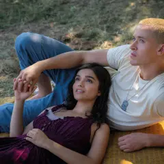 Ein junges Paar liegt im Gras. Sie halten Händchen, ein zarter Moment vor dem Hintergrund von "Die Tribute von Panem 5".