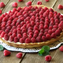 Pyszna tarta z malinami, udekorowana świeżymi listkami mięty. Idealna na letnie popołudnie.