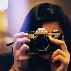 A person holds a Canon AE-1, a classic camera, ready to capture a moment. This camera is the best film for Canon AE-1 enthusiasts.