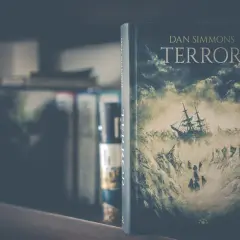 Okładka książki "Terror" Dana Simmonsa przedstawia żaglowiec walczący z lodowymi górami i sztormem.