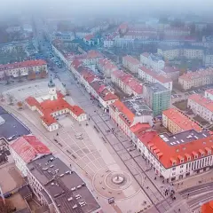 Widok z lotu ptaka na rynek Kościuszki w Białymstoku, otoczony kamienicami i budynkiem ratusza.